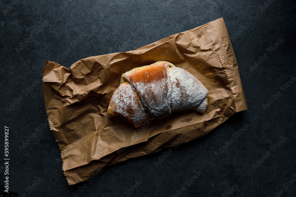 Delicious croissant on paper in natural light