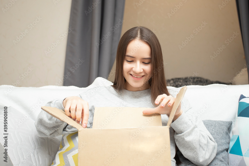 Happy young woman received a parcel order, unpacks a box at home Happy young woman received a parcel order, unpacks a box at home