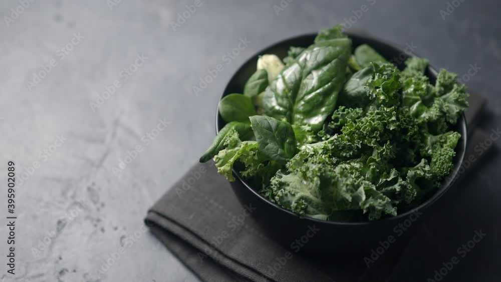The camera pans along a salad leaf dish in a black plate, a dark napkin and a black background. Place for text The camera pans along a salad leaf dish in a black plate, a dark napkin and a black background. Place for text