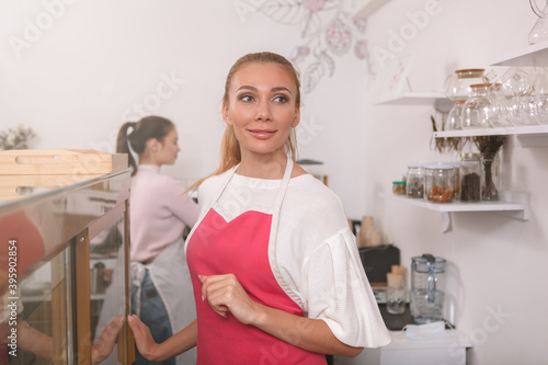 Gorgeous happy female barista smiling joyfully  working at her coffee shop