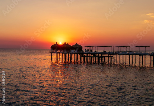 amazing picturesque view at a pier in sea with calm water and beautiful sunset on a background. Scenic costal view on shoreline with hotel in tourist season