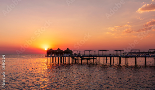 amazing picturesque view at a pier in sea with calm water and beautiful sunset on a background. Scenic costal view on shoreline with hotel in tourist season