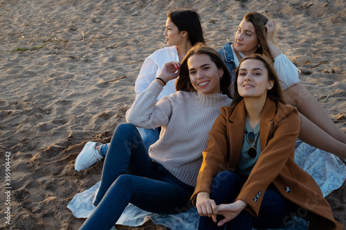 Group of young women in casual outfit on the beach, enjoying the sunset.