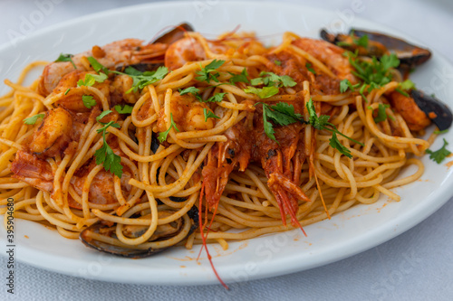 Colorful spaghetti with seafood on white plate.