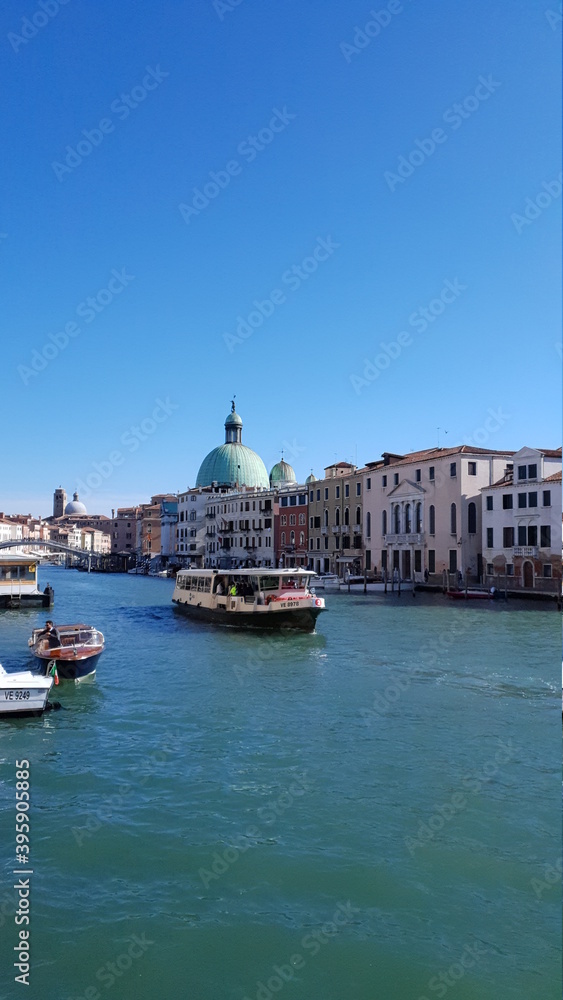 Grand Canal in Venice Italy. Panoramic view to picturesque landscape city and cathedral San Simeone Piccolo. Boat cutter on water. Sunny summery day with blue sky white clouds.
