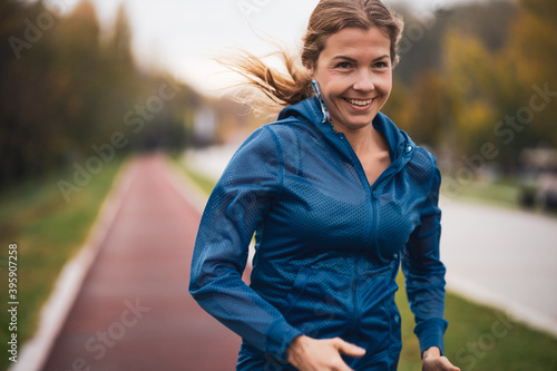 Fototapeta Naklejka Na Ścianę i Meble -  Beautiful adult woman is jogging outdoor on cloudy day in autumn.