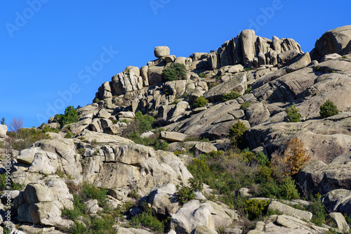 Paisaje de montaña con grandes rocas de granito erosionadas, cielo azul y plantas verdes. Pueblo Valdemanco Madrid, sierra de Guadarrama. photo