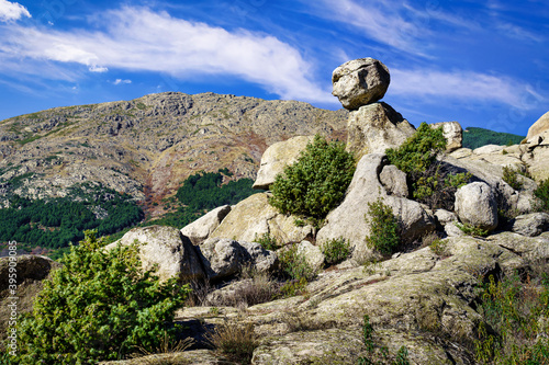 Paisaje de montaña con grandes rocas de granito erosionadas, cielo azul y plantas verdes. Pueblo Valdemanco Madrid, sierra de Guadarrama.