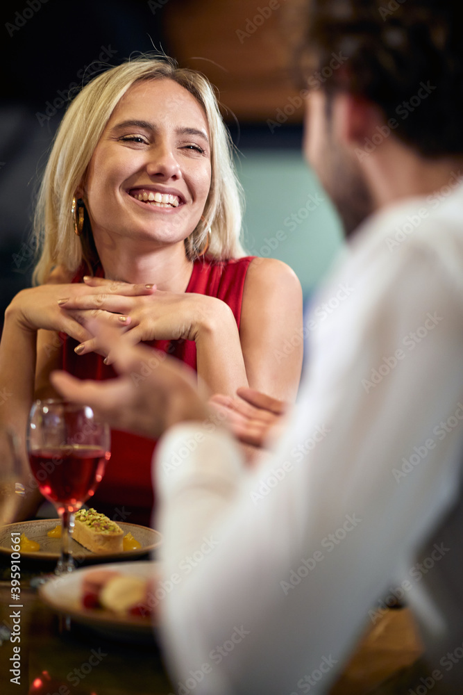young caucasian blonde smiling, charmed by her partner at dinner. young caucasian blonde smiling, charmed by her partner at dinner.