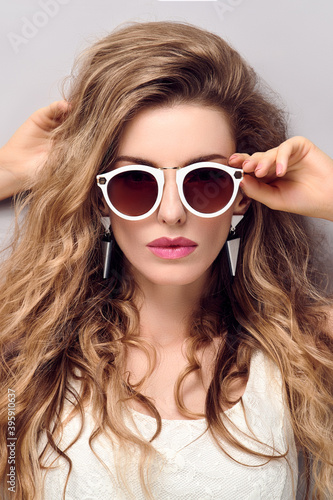 Beauty fashion woman portrait. Gorgeous young blonde with trendy wavy hair, makeup. Beautiful model girl, stylish sunglasses, fashionable hairstyle. Skincare make up concept