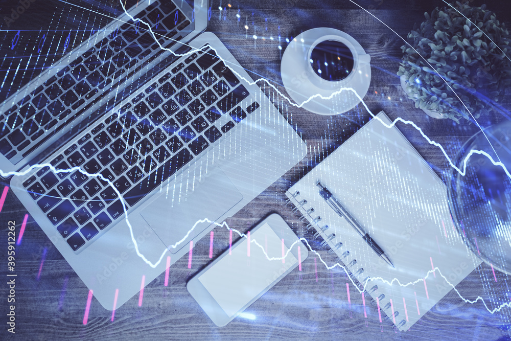 Financial market graph and top view computer on the desktop background. Double exposure. Investment concept. Financial market graph and top view computer on the desktop background. Double exposure. Investment concept.