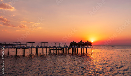 amazing picturesque view at a pier in sea with calm water and beautiful sunset on a background. Scenic costal view on shoreline with hotel in tourist season © Yaroslav