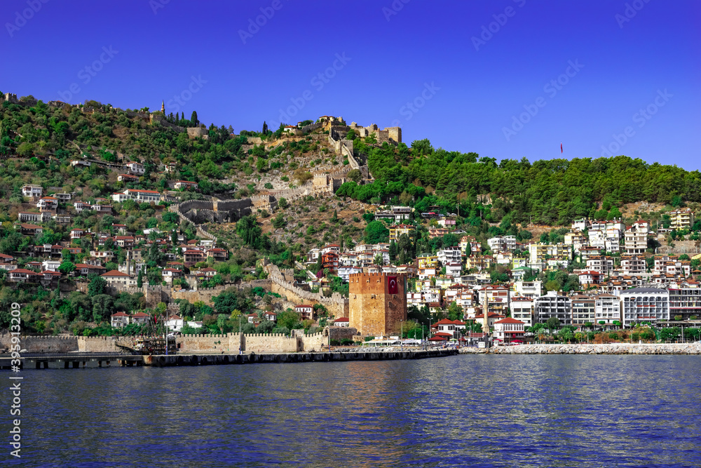 View from the sea to the Old City of Alanya (Turkey). Kizil Kule, Alanya Kalesi, ancient wall and modern cottages on the Mediterranean coast