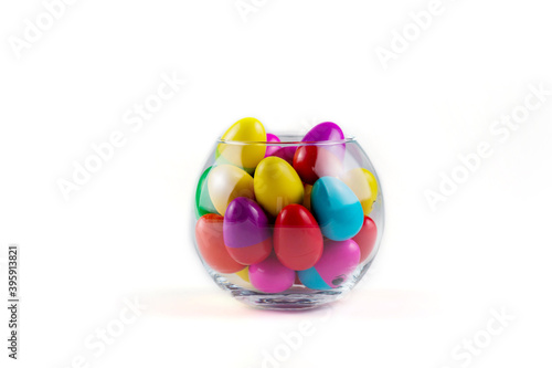 Colorful Plastic Easter Eggs in a glass vase on white background © галина шарапова