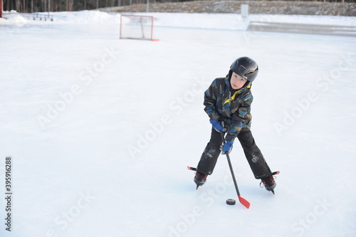 A young ice hockey amateur player on ice rink playing hockey with a stick in winter in Sweden