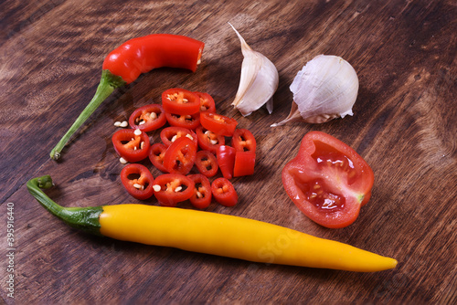 Red and yellow chilli paprika with garlic and cherry tomato on wooden background