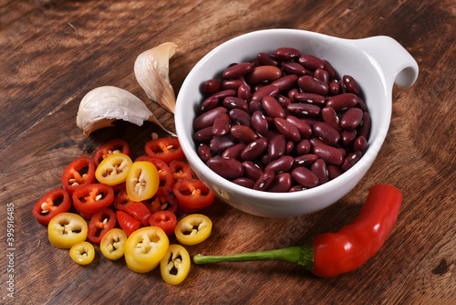 Red and yellow chilli paprika with garlic, cherry tomato an beans in a bowl on wooden background