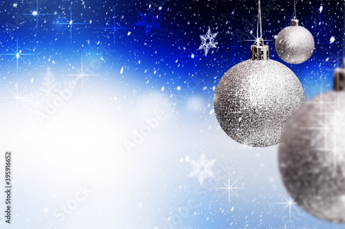 Obraz na płótnie Three glass silver Christmas ornaments hanging over snowy blue background with snowflakes, sparkles. Merry Xmas and Happy New Year greeting card. Copy space. w salonie