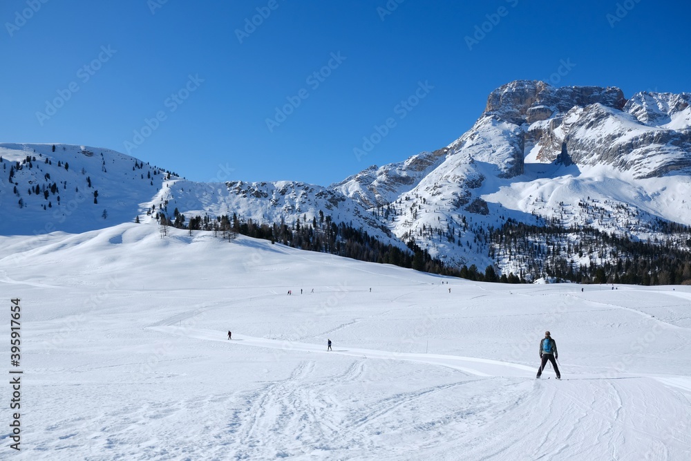 Beautiful winter mountain landscape with cross-country ski tracks and silhouette of running skiers. Piazza Prato plateau, Sexten Dolomites, South Tyrol, Italy