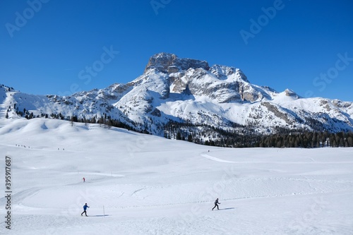 Beautiful winter mountain landscape with cross-country ski tracks and silhouette of running skiers. Piazza Prato plateau, Sexten Dolomites, South Tyrol, Italy © Iwona