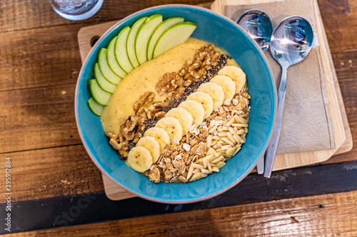 Healthy smoothie bowl breakfast with granola, cut banana, sliced apples, and various types of nuts photo