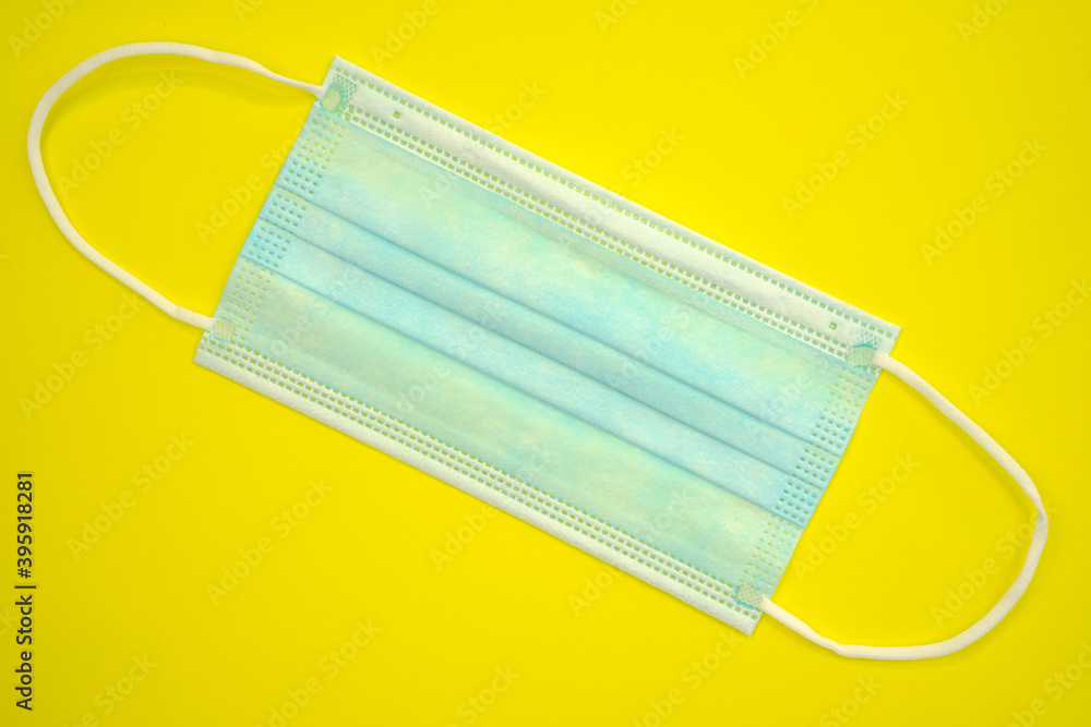 Antibacterial medical mask of blue color on a yellow background. Coronavirus Protection concept. Antibacterial medical mask of blue color on a yellow background. Coronavirus Protection concept.