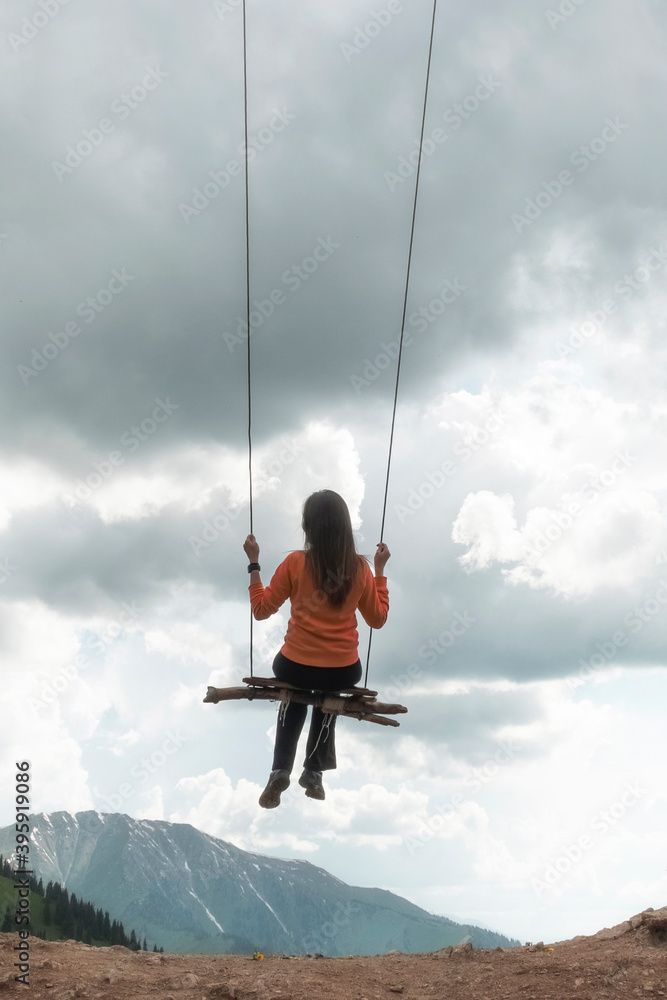 The girl swings on a swing over the mountains, a feeling of flight and freedom. The girl swings on a swing over the mountains, a feeling of flight and freedom.