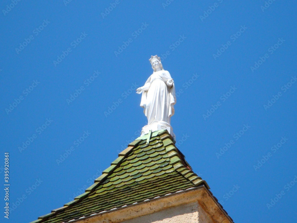 Obraz premium white statue of the virgin mary against blue sky