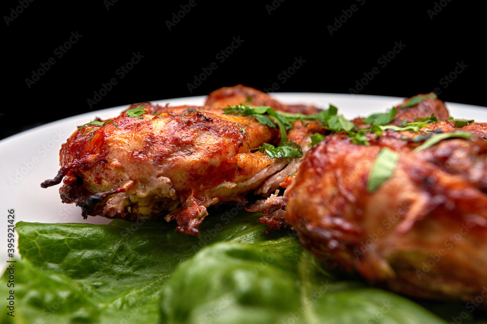 Fried chicken with a delicious crispy crust, with lettuce, on a white plate, on a black background
