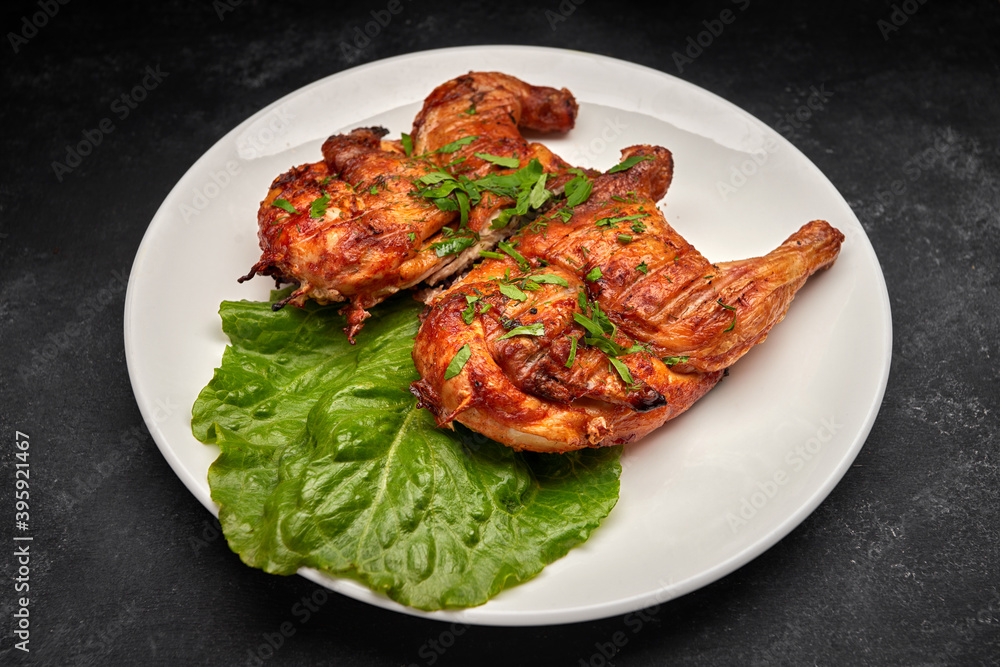 Fried chicken with a delicious crispy crust, with lettuce, on a white plate, on a black background Fried chicken with a delicious crispy crust, with lettuce, on a white plate, on a black background