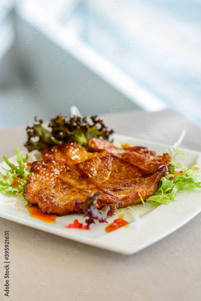 main course of Pan-fried Pork Chop with Soy Sauce served on lettuce on a white plate
