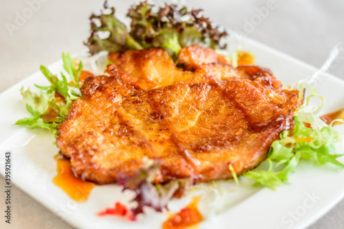 main course of Pan-fried Pork Chop with Soy Sauce served on lettuce on a white plate