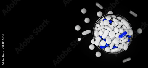 Fototapeta Naklejka Na Ścianę i Meble -  blue pill capsules in a glass bowl among white pills top view. free panoramic space