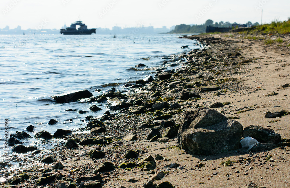 Fototapeta premium Stones on the beach line (coast) river, and ship (ferry boat) on the background