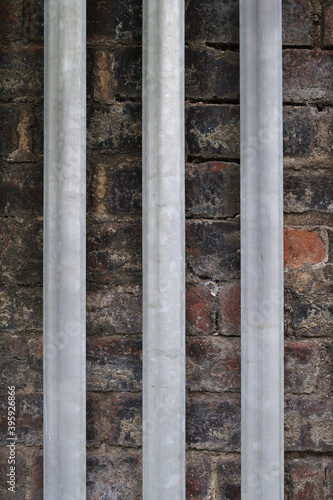 Detail of Vertical Steel Fencing against Old Brick Wall 