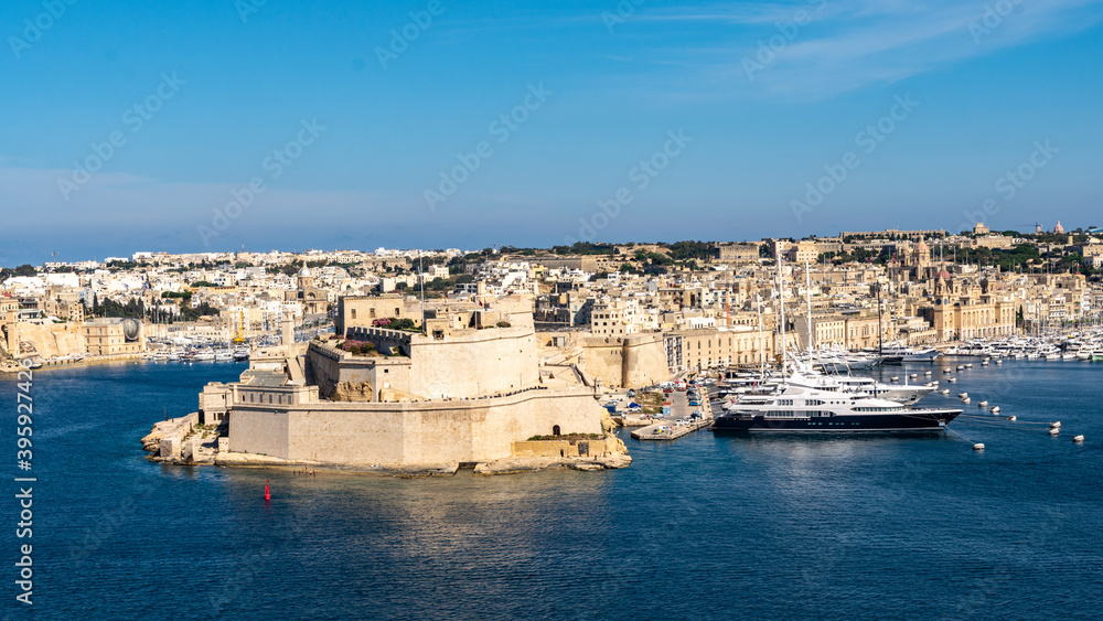 The city of Birgu known as Vittoriosa with Fort Saint Angelo at its tip. There are yachts moored along side in the marina.