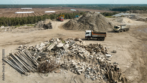 Aerial view of trucks near heap of waste on construction site. Fragments of concrete, wire, and rocks.