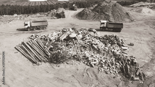 Top view of trucks near heap of waste on construction site. Fragments of concrete, wire, and rocks. Heap of ground.