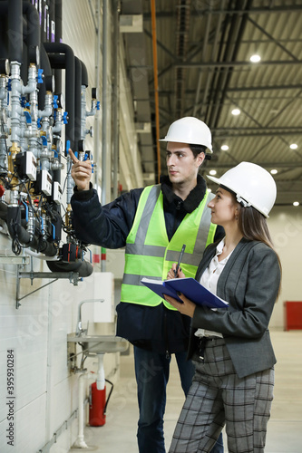 Wallpaper Mural Portrait of a female factory manager in a white hard hat and business suit and factory engineer in work clothes. Controlling the work process in the manufacture. Torontodigital.ca