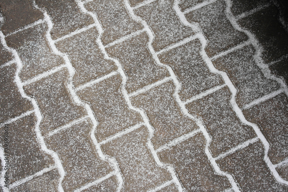 The first snow on the tile-paving stones, the material is an abstract background. The first snow on the tile-paving stones, the material is an abstract background.