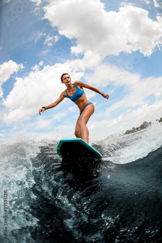beautiful woman rides down the river wave on wake boar