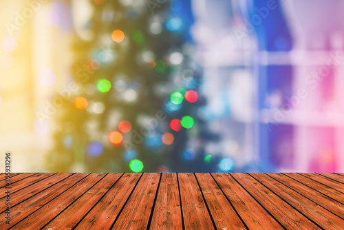 Wooden table against the background of a blurred Christmas tree. Empty wooden board and Christmas background. Colorful bokeh lights