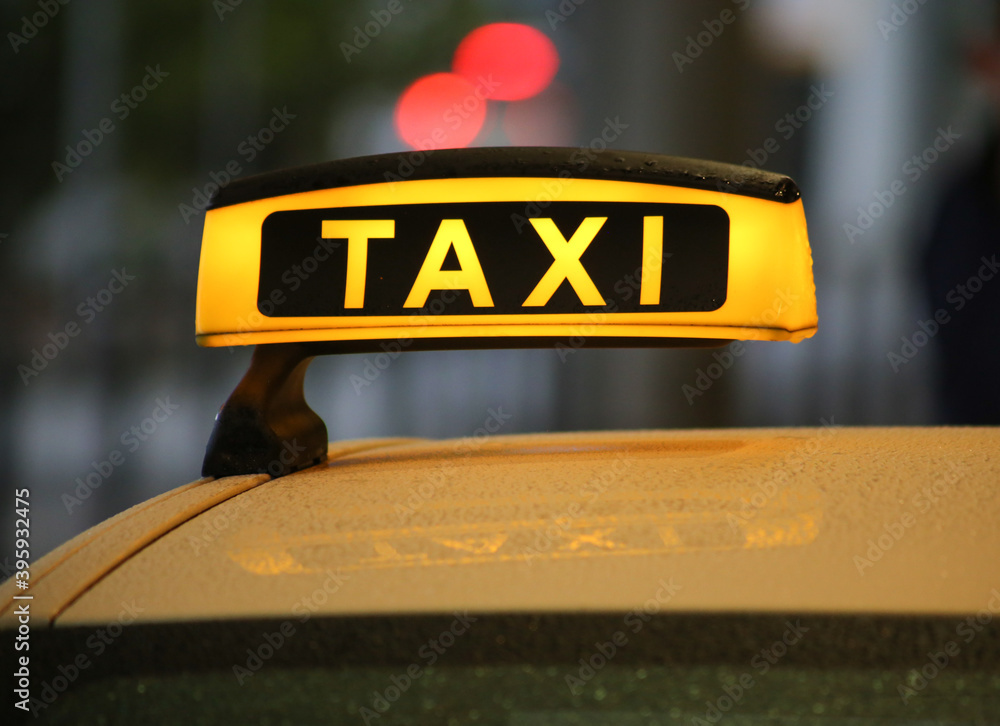 Taxi sign on yellow cab on rainy day