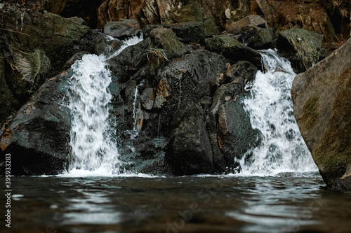 Small cascading waterfall among the rocks and forest. Beautiful mountain landscape. Copy  empty space for text