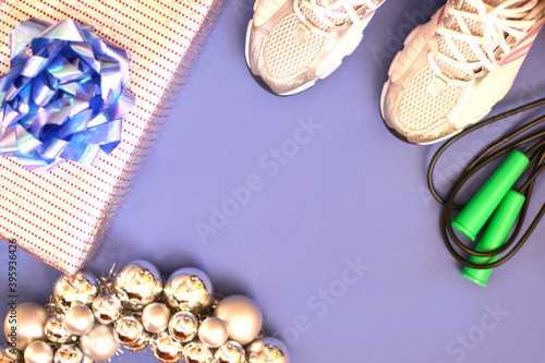Sport equipment (rope, sneakers) with new year decorations on blue background. Flat lay, top view with copy space. Fitness, sport and healthy lifes.