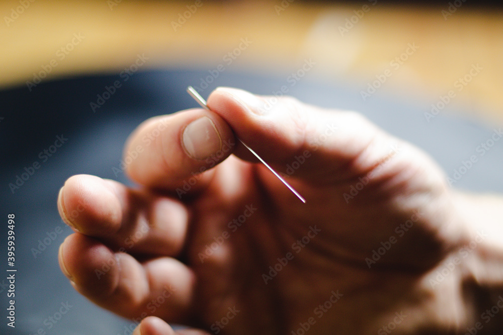 close up of a hand holding an acupuncture needle close up of a hand holding an acupuncture needle