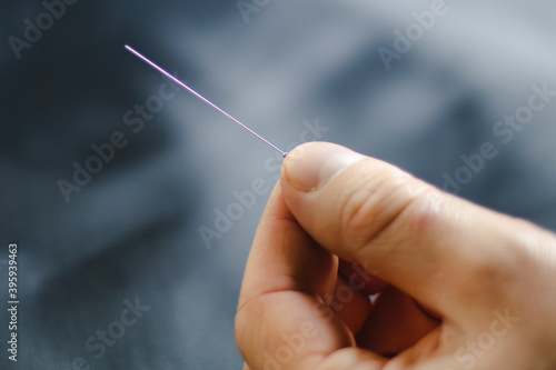 close up of a hand holding an acupuncture needle