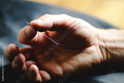 close up of a hand holding an acupuncture needle