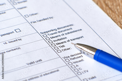 Application form for a Schengen visa. The form and pen are on the table.