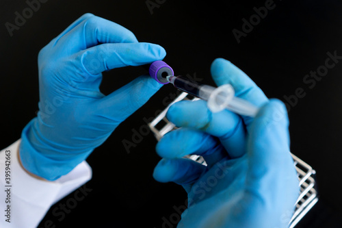 ..The hands of a laboratory technician with test tubes samples and shelves with other samples / laboratory technicians that collect test tubes for Detection photo